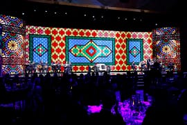 Wide stage view with live musicians, a classic race car, and a large colorful patterned backdrop during the FIA – Motorsport Award Ceremony.