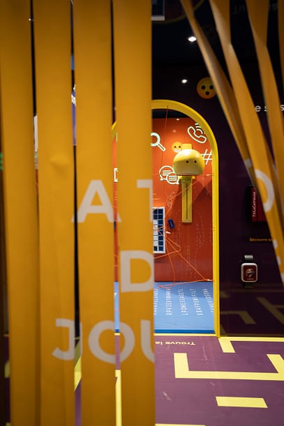 Entrance to an immersive space framed by flexible curtain elements and playful scenography, immediately drawing visitors into a visually engaging environment.
